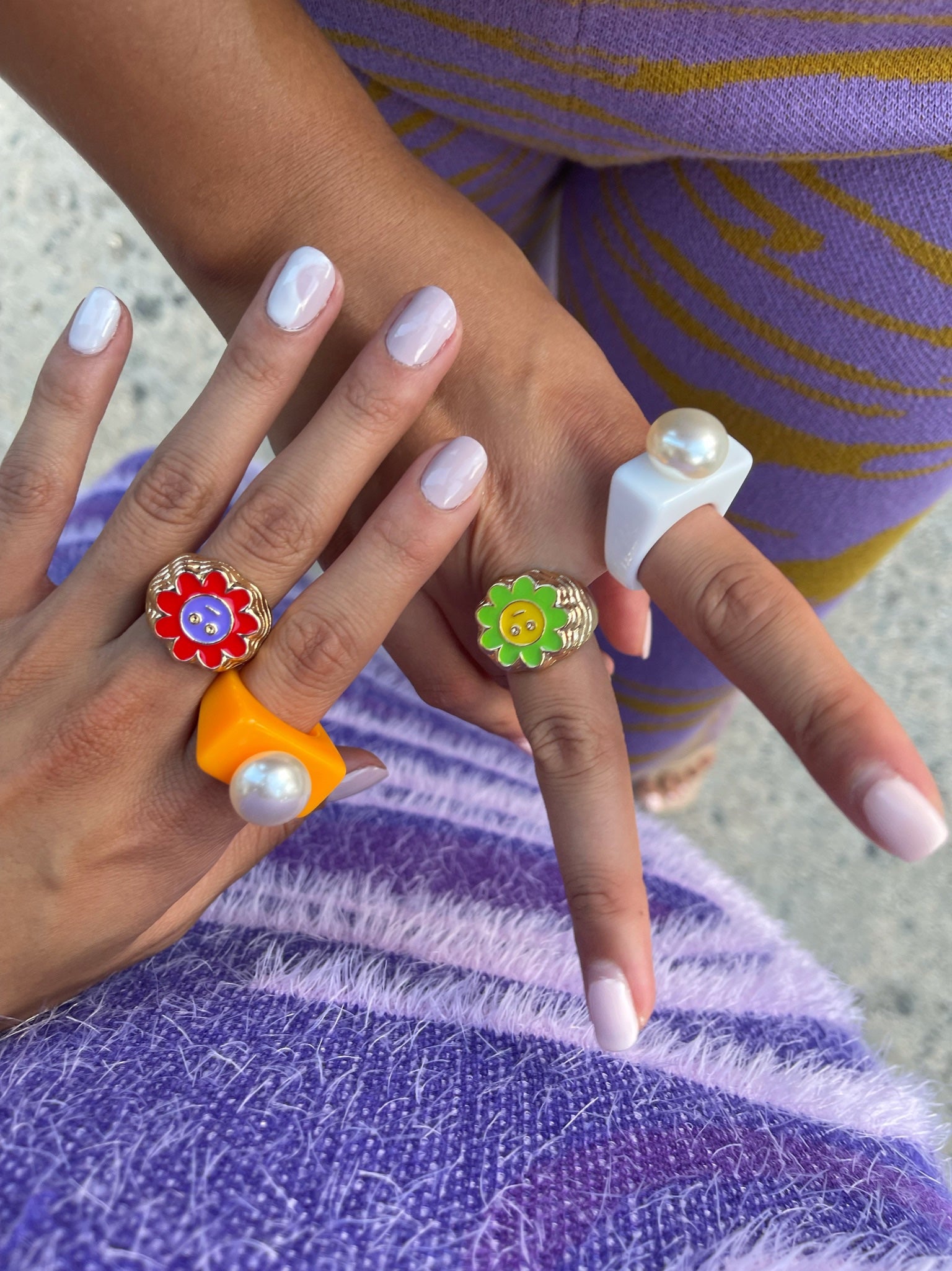 Two women are standing with their fingers crossed together. They are each wearing two rings.